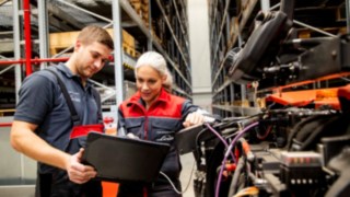 Zwei Service-Techniker von Linde Material Handling schauen auf einen Laptop neben einem Fahrzeug.